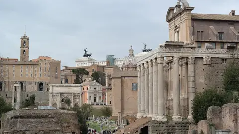 The Roman Forum with the columns of the Temple of Antoninus and Faustina on the right, the Arch of Septimius Severus behind, and the Vittoriano rising over Piazza Venezia in the distance