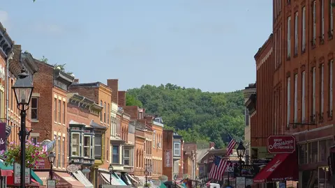 Brick storefronts and flags along Main Street in Galena, Illinois, with a wooded bluff at the end of the street