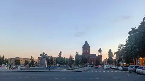 Vartanants Square in Gyumri at dusk, with the Vardan Mamikonian equestrian statue on the left and the red tuff Holy Saviour's Church across the road
