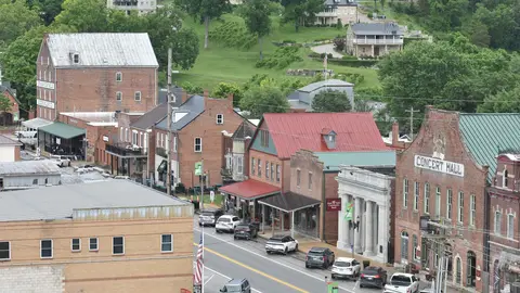 Brick storefronts along First Street in Hermann, Missouri, including Concert Hall, with houses on the green hillside behind